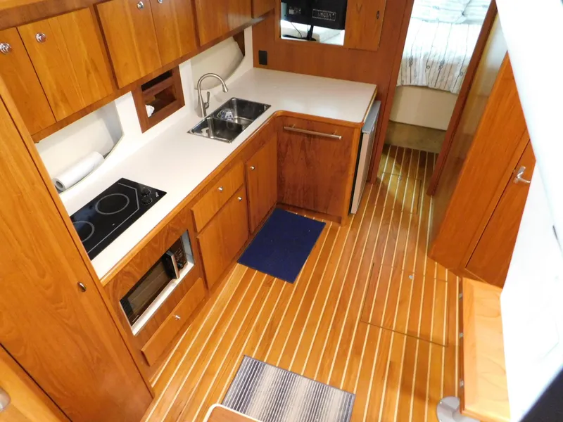 Slide: The Image of 1999 Tiara Yachts 3500 Express galley with wood cabinetry, sink, stove, and microwave. - 23