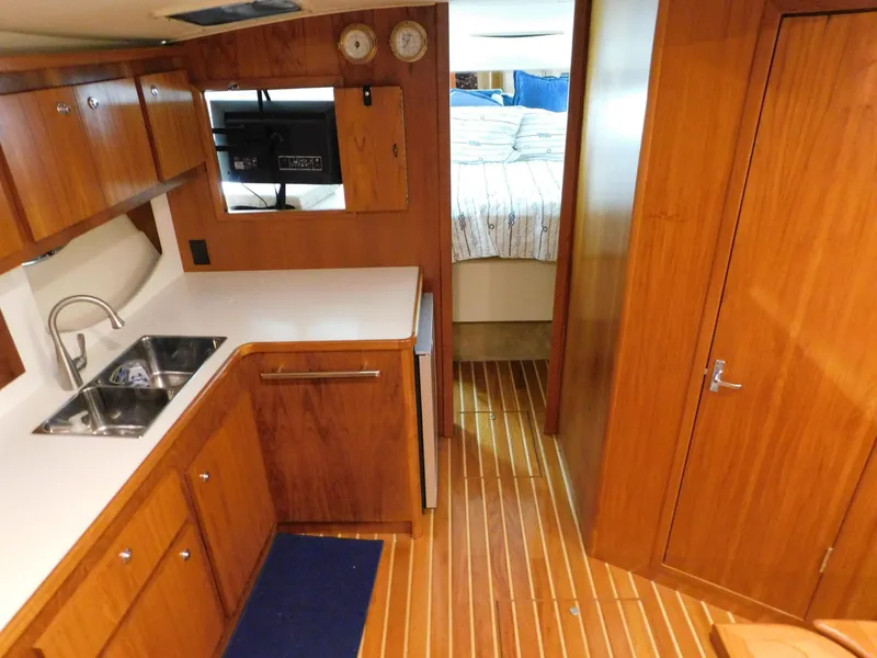 Slide: The Image of 1999 Tiara Yachts 3500 Express interior with wood cabinetry, sink, and cozy bedroom. - 25