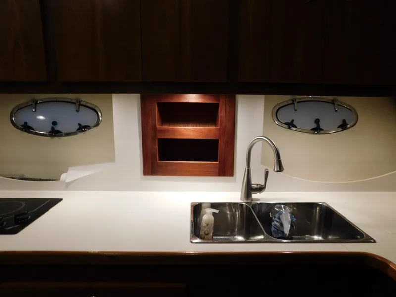 Slide: The Image of 1999 Tiara Yachts 3500 Express kitchen with sink, faucet, and porthole windows. - 32