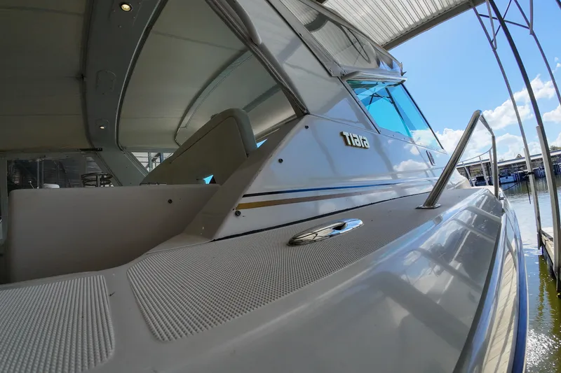 Slide: The Image of 1999 Tiara Yachts 3500 Express docked under a canopy, showcasing sleek design and craftsmanship. - 79