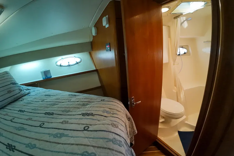 Slide: The Image of 1999 Tiara Yachts 3500 Express interior with cozy bedroom and compact bathroom. - 90