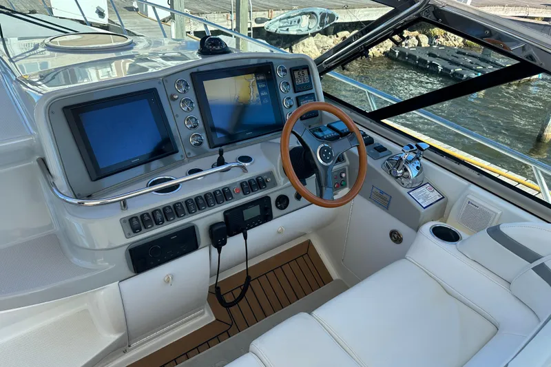Slide: The Image of 2004 Formula 48 Yacht cockpit with navigation screens and steering wheel, docked by the water. - 34