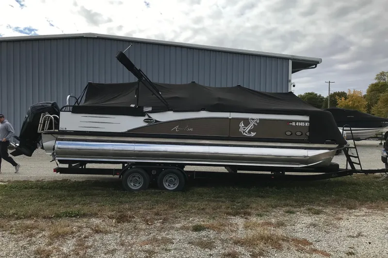 Slide: The Image of 2019 Avalon Catalina VRL 25' pontoon boat on trailer, covered, near metal building. - 16