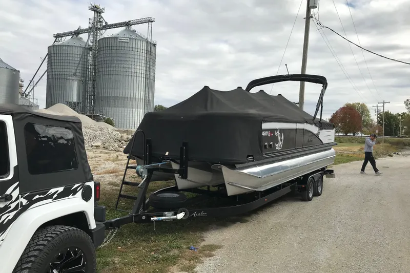 Slide: The Image of 2019 Avalon Catalina VRL 25' boat on trailer, covered, near silos and Jeep. - 18