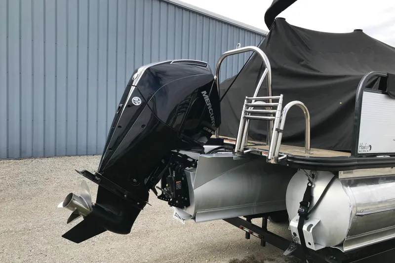 Slide: The Image of 2019 Avalon Catalina VRL 25' boat with Mercury outboard motor, parked near a metal building. - 6
