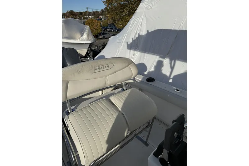 Slide: The Image of 2001 Boston Whaler 230 Outrage boat seat with white upholstery and logo. - 4