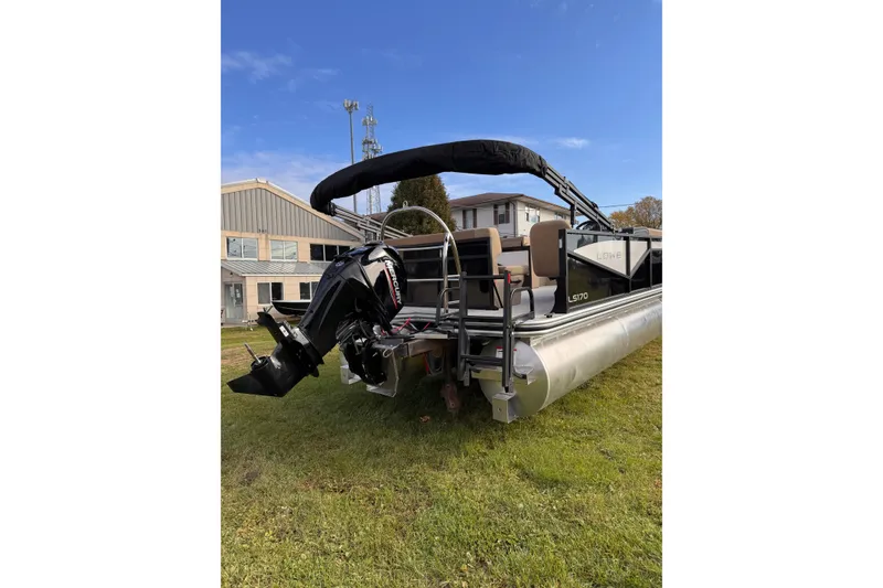 Slide: The Image of 2026 Lowe LS 170 pontoon boat with Mercury outboard motor on grassy area. - 5