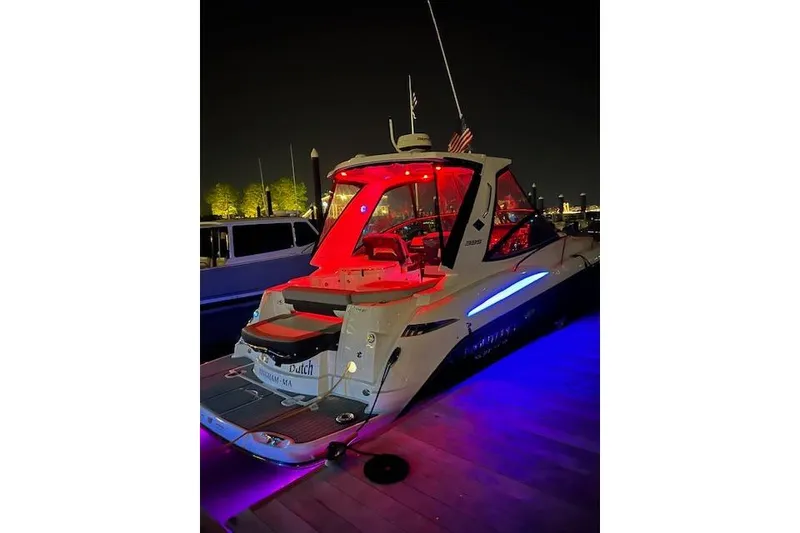 Slide: The Image of 2021 Monterey 335 Sport Yacht illuminated at night with vibrant red and blue lights. - 8