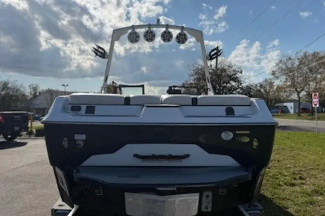 Slide: The Image of 2022 Axis A24 boat rear view with speakers, parked outdoors under a cloudy sky. - 4