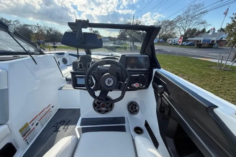 Slide: The Image of 2022 Axis A24 boat interior with steering wheel, dashboard, and seating under a cloudy sky. - 7