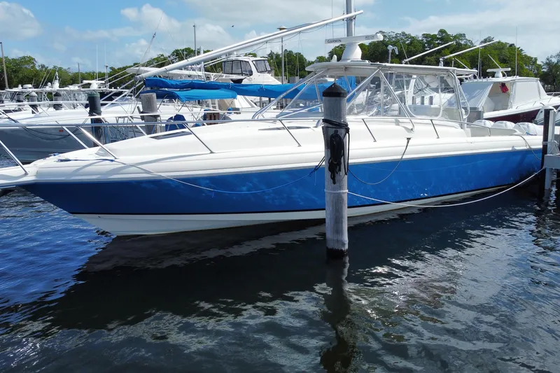 Slide: The Image of 2006 Intrepid 377 boat docked in marina, featuring sleek blue and white design. - 0
