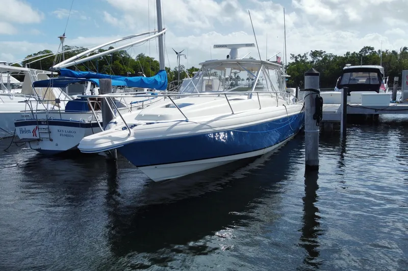 Slide: The Image of 2006 Intrepid 377 boat docked in marina, blue and white design, calm water. - 2