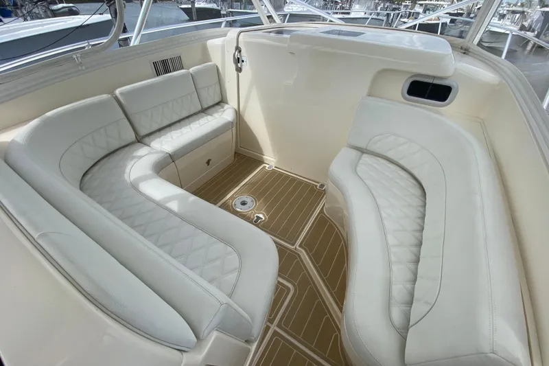 Slide: The Image of 2006 Intrepid 377 boat interior with white cushioned seating and wooden flooring. - 24
