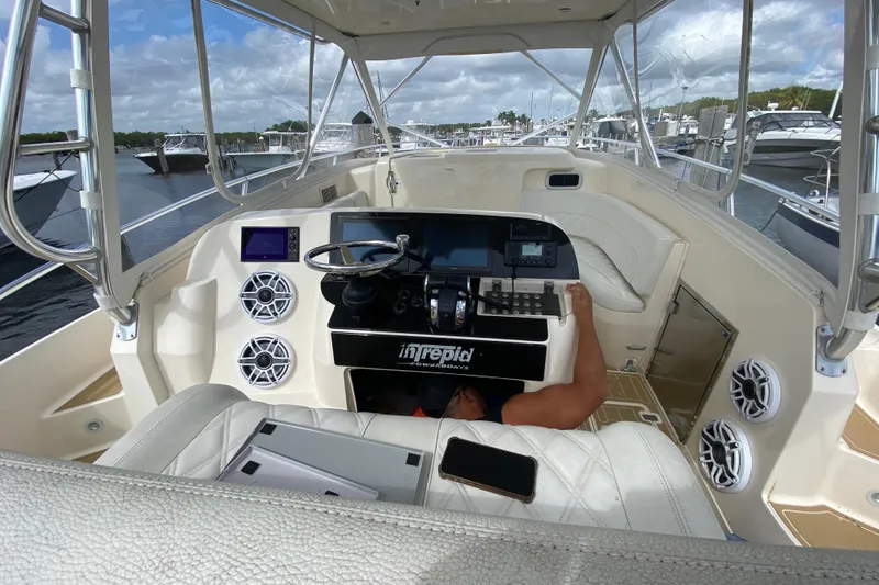 Slide: The Image of 2006 Intrepid 377 boat cockpit with steering wheel, electronics, and seating at marina. - 30