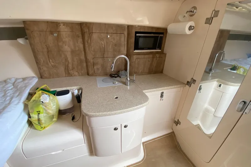 Slide: The Image of 2006 Intrepid 377 boat interior with kitchenette, sink, microwave, and storage cabinets. - 38