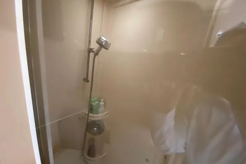 Slide: The Image of Shower area inside a 2006 Intrepid 377 boat, featuring a handheld showerhead and toiletries. - 41