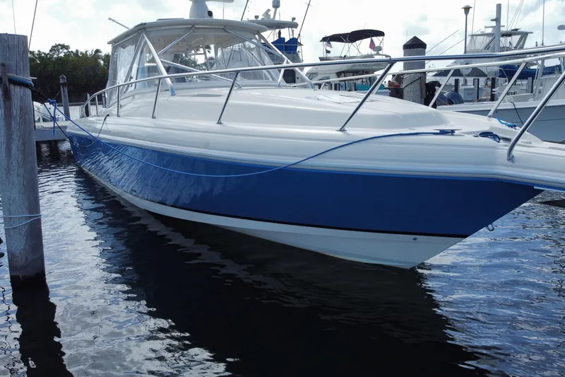 Slide: The Image of 2006 Intrepid 377 boat docked, featuring sleek blue and white design. - 6