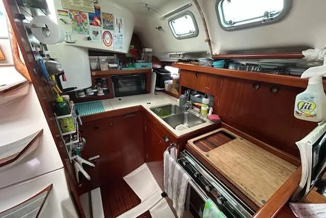 Slide: The Image of Interior of 1994 Beneteau Oceanis 351 sailboat kitchen with wooden cabinetry and appliances. - 26