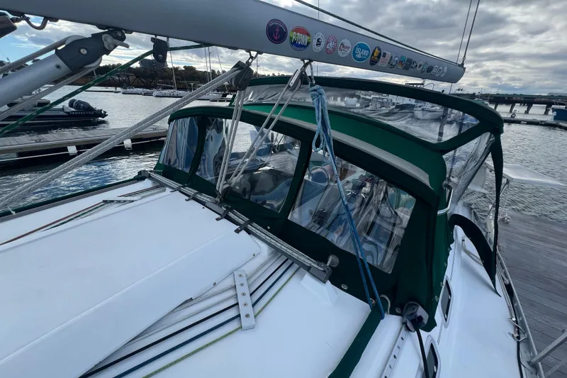 Slide: The Image of 1994 Beneteau Oceanis 351 sailboat docked, featuring green canopy and mast with stickers. - 6