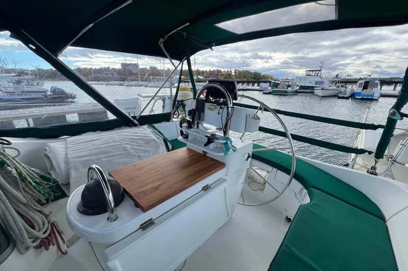 Slide: The Image of Cockpit of 1994 Beneteau Oceanis 351 sailboat docked at marina, featuring steering wheel and navigation equipment. - 7