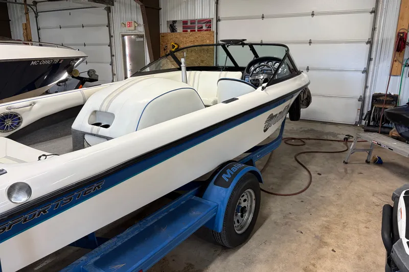 Slide: The Image of 1998 Malibu Sportster boat in garage, white with blue accents, on a trailer. - 3