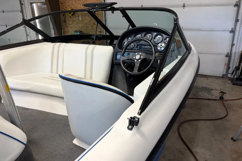 Slide: The Image of 1998 Malibu Sportster boat interior with white seating and dashboard in a garage. - 5