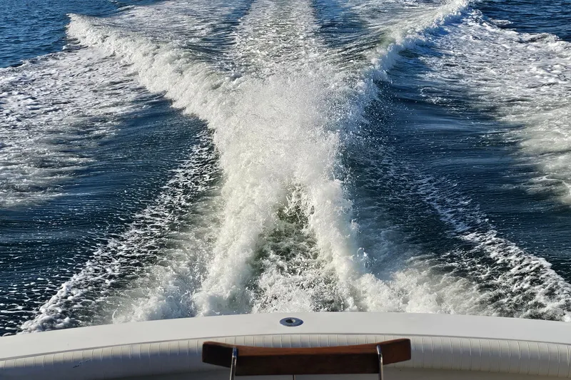 Slide: The Image of Wake trail behind a 1980 Bertram 42 Convertible boat on open water. - 10