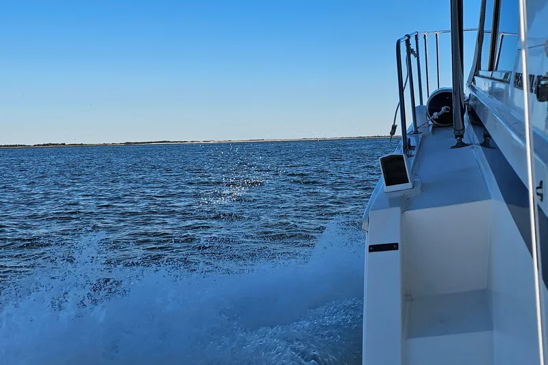 Slide: The Image of 1980 Bertram 42 Convertible cruising on open water under clear blue sky. - 11