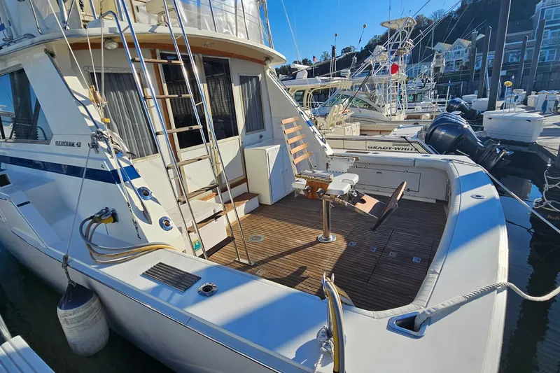 Slide: The Image of 1980 Bertram 42 Convertible yacht docked, featuring a spacious deck and fishing chair. - 13