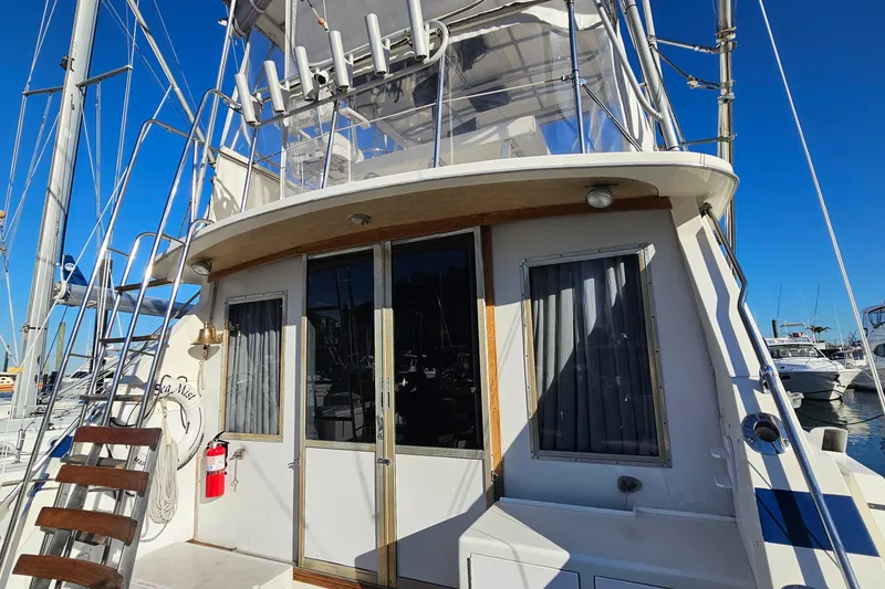 Slide: The Image of 1980 Bertram 42 Convertible yacht docked, featuring upper deck and cabin entrance. - 18