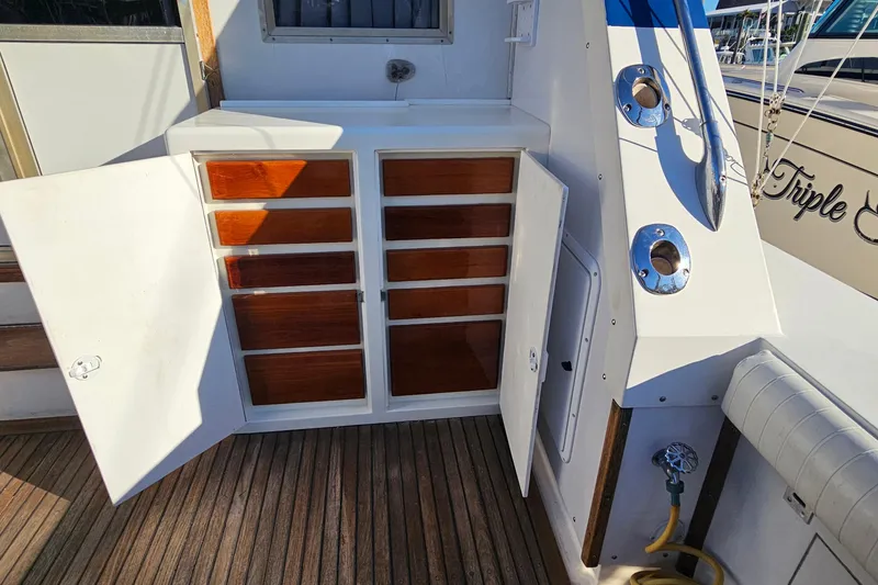Slide: The Image of Open storage cabinet on 1980 Bertram 42 Convertible yacht deck, featuring wooden shelves. - 19
