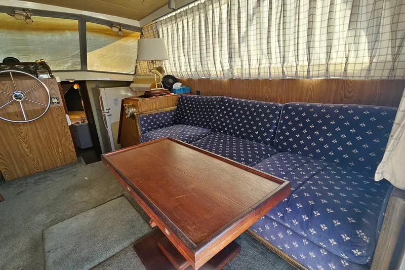 Slide: The Image of Interior of 1980 Bertram 42 Convertible with blue patterned sofa and wooden table. - 21