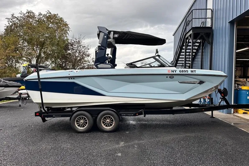The Image of 2023 Nautique Super Air Nautique G23 Paragon boat on trailer, parked outside a building. - 1
