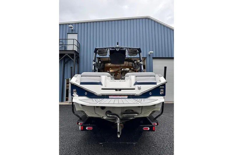 Slide: The Image of 2023 Nautique Super Air Nautique G23 Paragon boat, rear view, parked near blue building. - 2