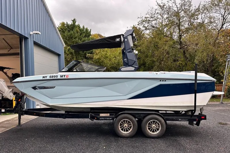 Slide: The Image of 2023 Nautique Super Air Nautique G23 Paragon boat on trailer near blue garage. - 3