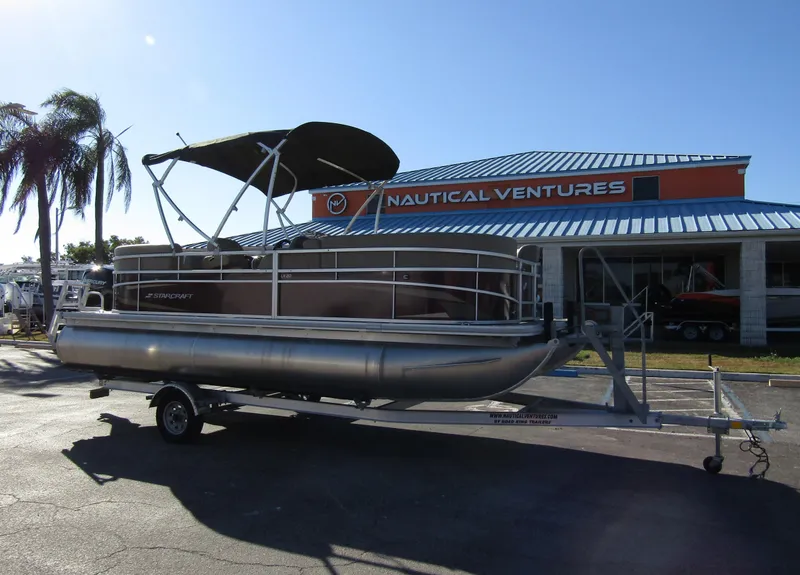 Slide: The Image of 2024 Starcraft LX 20 R pontoon boat on trailer at Nautical Ventures dealership. - 6