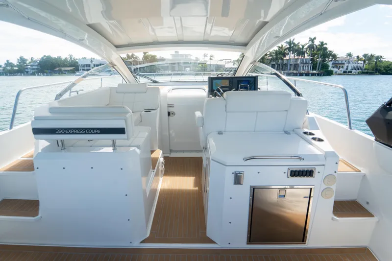 Slide: The Image of 2018 Cruisers Yachts 390 Express Coupe interior with modern helm and seating, docked by waterfront homes. - 52