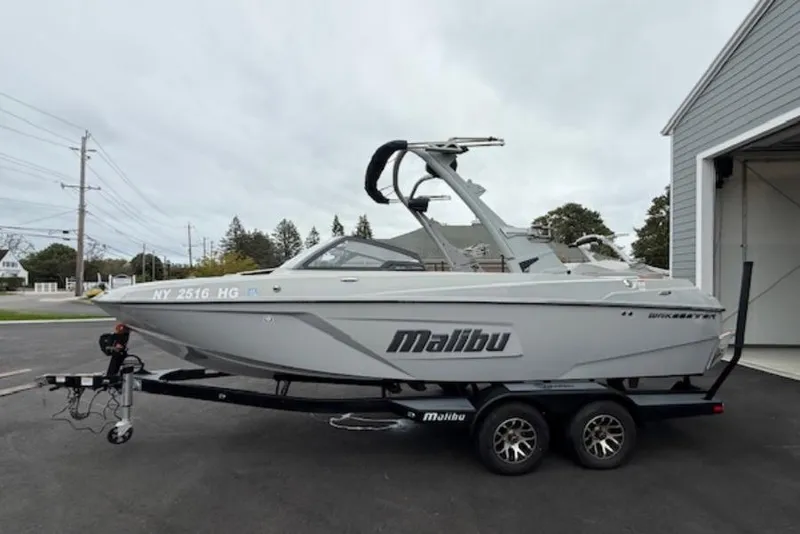 The Image of 2022 Malibu Wakesetter 22 LSV boat on trailer, parked outside a garage. - 1