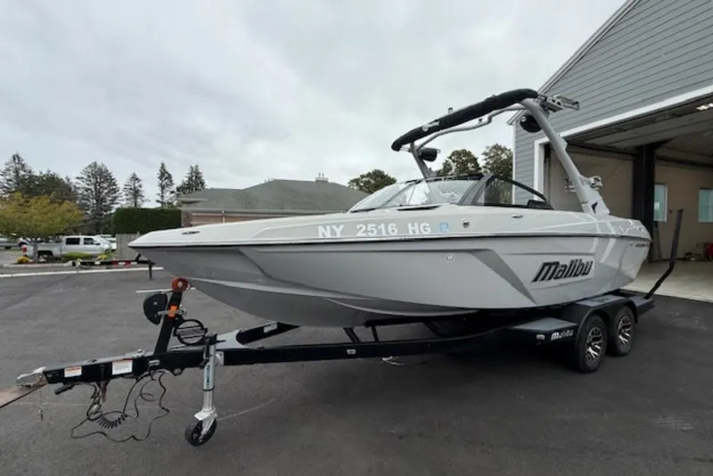 Slide: The Image of 2022 Malibu Wakesetter 22 LSV boat on trailer, parked outside a garage. - 2