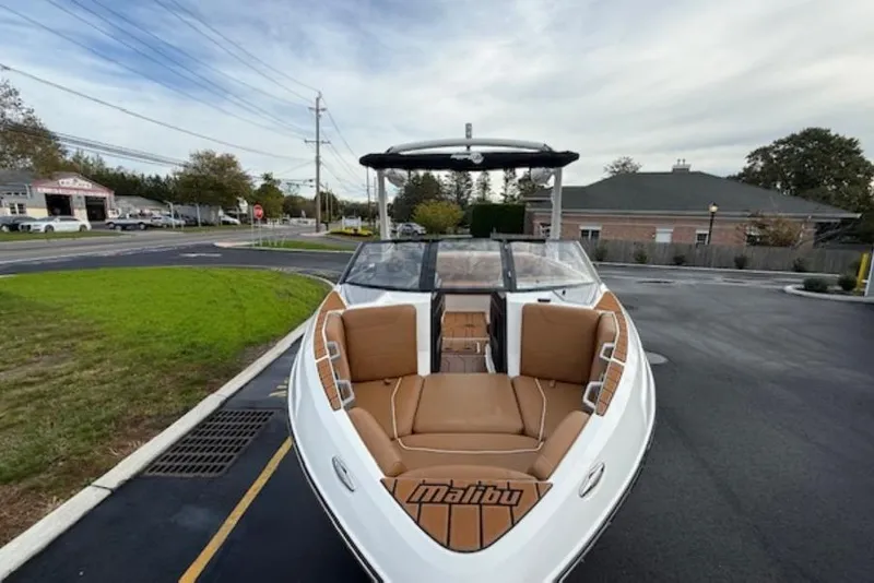 Slide: The Image of 2021 Malibu Wakesetter 22 LSV boat with tan seating, parked on a paved area. - 5