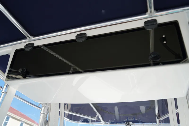 Slide: The Image of T-top storage compartment on a 2002 Fish Hawk 230 CC boat, featuring a sleek black panel. - 24