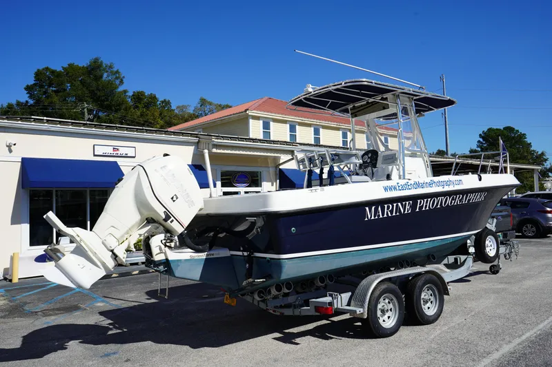 Slide: The Image of 2002 Fish Hawk 230 CC boat on trailer, parked outside a marine shop. - 3