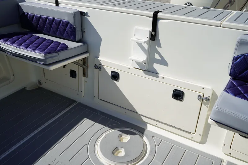 Slide: The Image of Interior of 2002 Fish Hawk 230 CC boat with purple cushioned seats and storage compartments. - 8