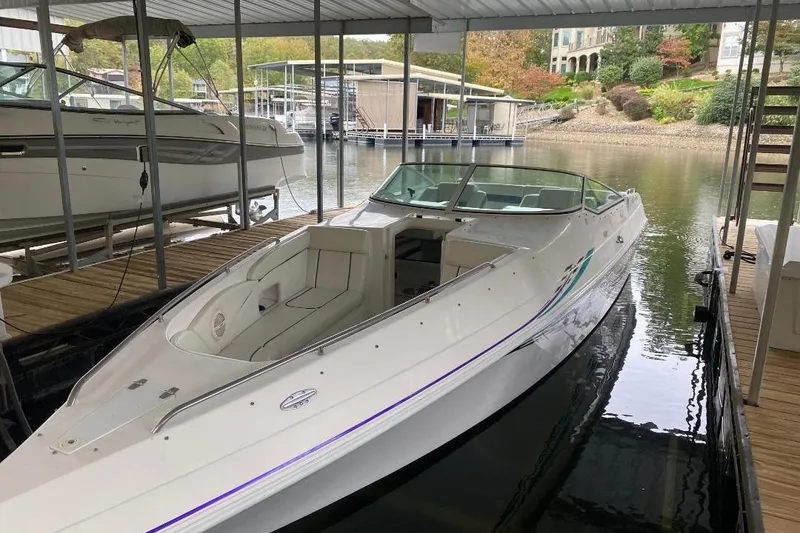 Slide: The Image of 2004 Envision 2900 Combo boat docked in a covered marina, surrounded by calm water. - 4
