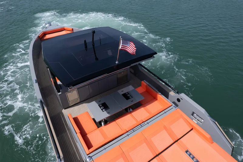 Slide: The Image of 2023 De Antonio Yachts D50 with orange seating, American flag, cruising on water. - 31