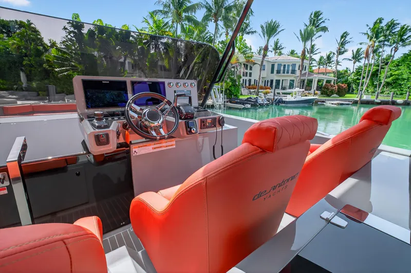 Slide: The Image of 2023 De Antonio Yachts D50 helm with red seats, modern controls, and waterfront view. - 40