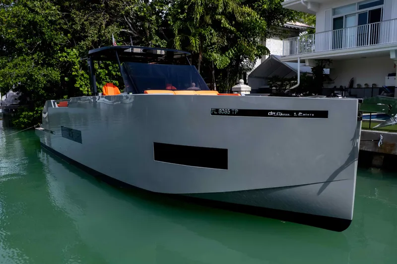 Slide: The Image of 2023 De Antonio Yachts D50 docked near a modern waterfront home. - 8