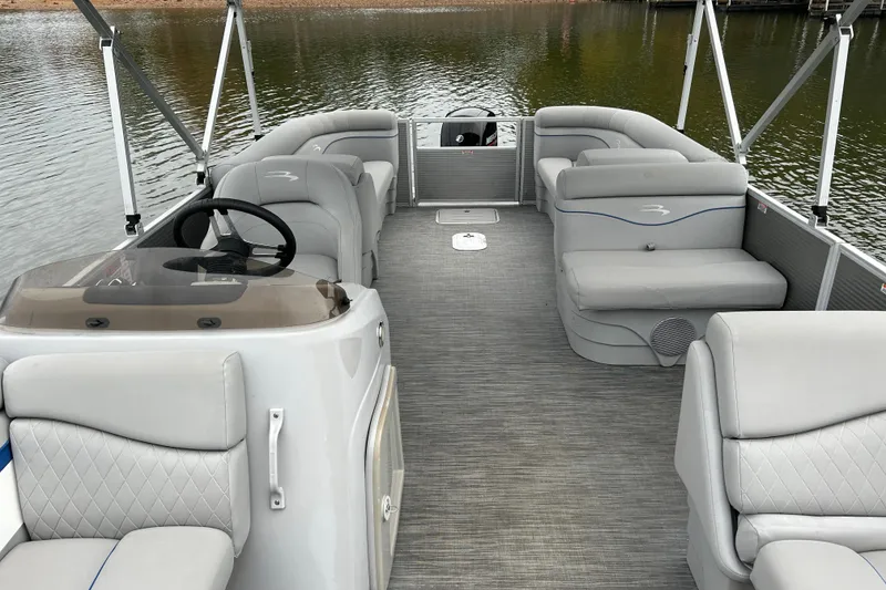 Slide: The Image of 2023 Bennington 22 SSR pontoon boat interior with gray seating and steering wheel on a lake. - 13