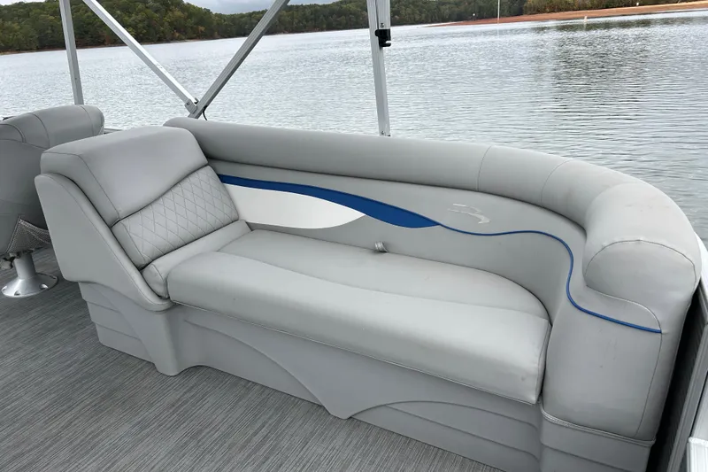 Slide: The Image of 2023 Bennington 22 SSR pontoon boat with gray seating and blue accents on a calm lake. - 15