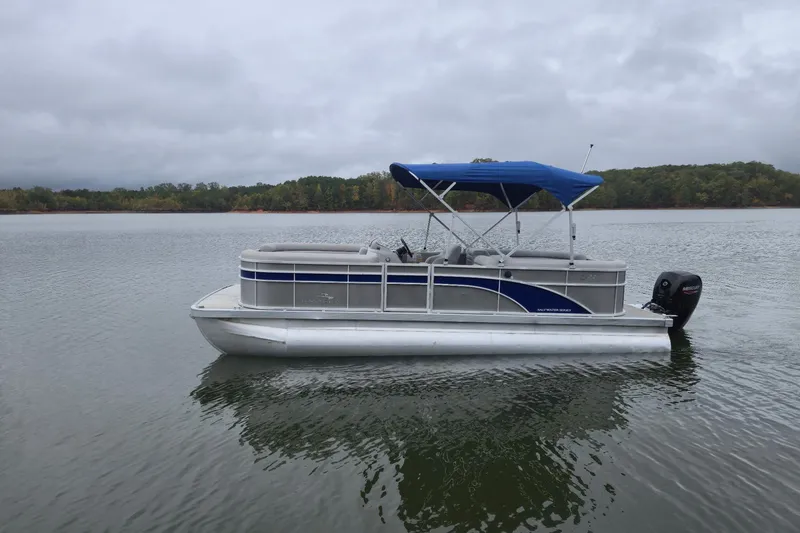 Slide: The Image of 2023 Bennington 22 SSR pontoon boat on a calm lake with overcast skies. - 5